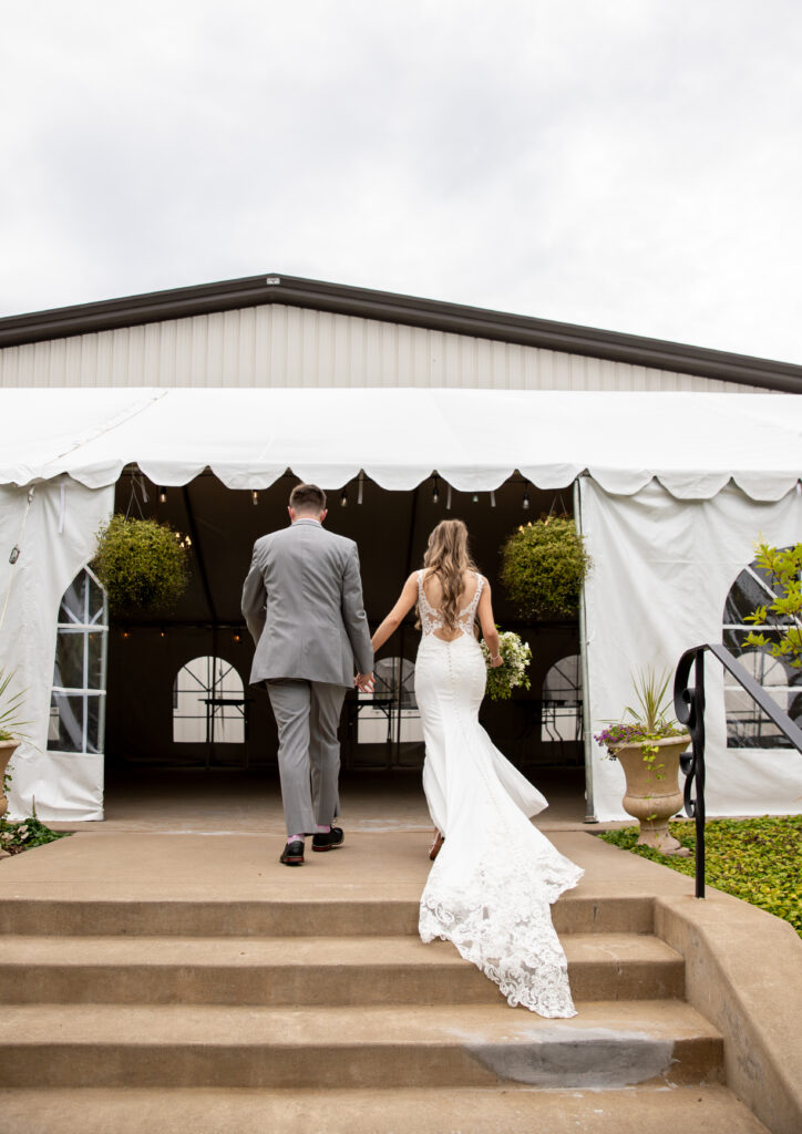 Bride and groom walking into a white tented venue on a cloudy day.